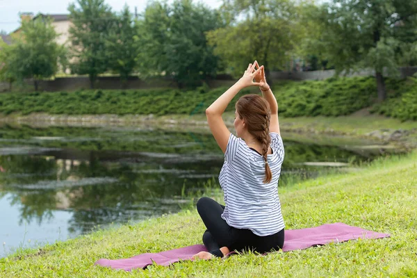 Jeune belle femme faisant de l'exercice de yoga dans un parc vert. Style de vie sain et concept de fitness . — Photo