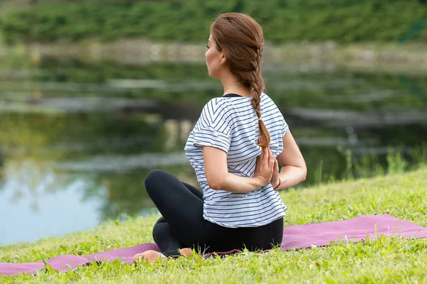 Ung vacker kvinna som motionerar yoga i grön park. Friska livsstil och fitness koncept. — Stockfoto