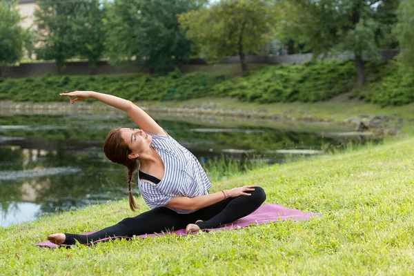 Junge schöne Frau macht Yoga-Übungen im grünen Park. gesunder Lebensstil und Fitness-Konzept. — Stockfoto