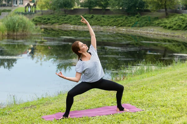 Jeune belle femme faisant de l'exercice de yoga dans un parc vert. Style de vie sain et concept de fitness . — Photo