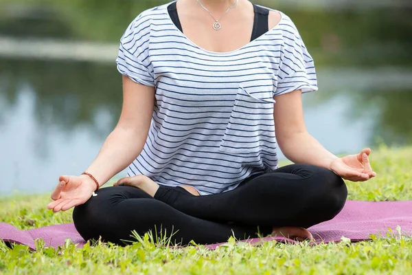 Ung vacker kvinna som motionerar yoga i grön park. Friska livsstil och fitness koncept. — Stockfoto