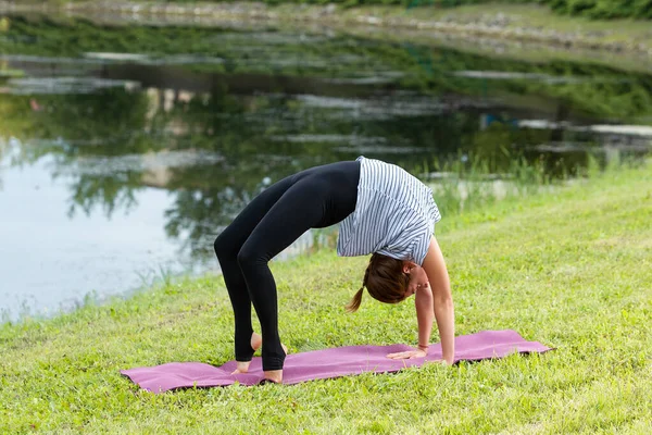 Jovem mulher bonita fazendo exercício de ioga no parque verde. Estilo de vida saudável e conceito de fitness . — Fotografia de Stock