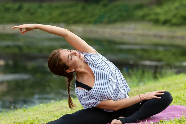 Junge schöne Frau macht Yoga-Übungen im grünen Park. gesunder Lebensstil und Fitness-Konzept. — Stockfoto