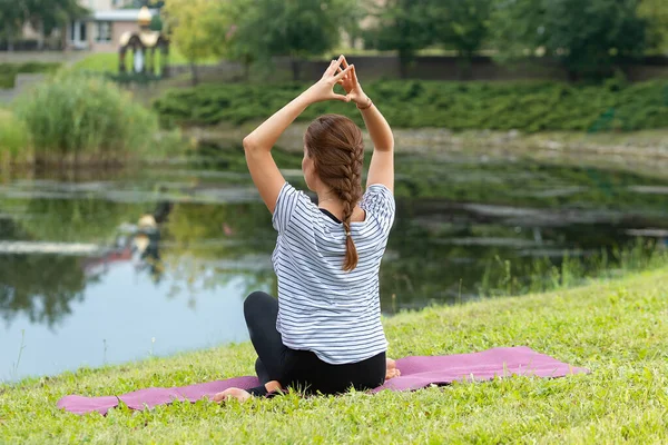 Jeune belle femme faisant de l'exercice de yoga dans un parc vert. Style de vie sain et concept de fitness . — Photo