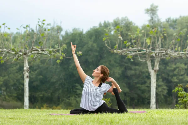 Junge schöne Frau macht Yoga-Übungen im grünen Park. gesunder Lebensstil und Fitness-Konzept. — Stockfoto