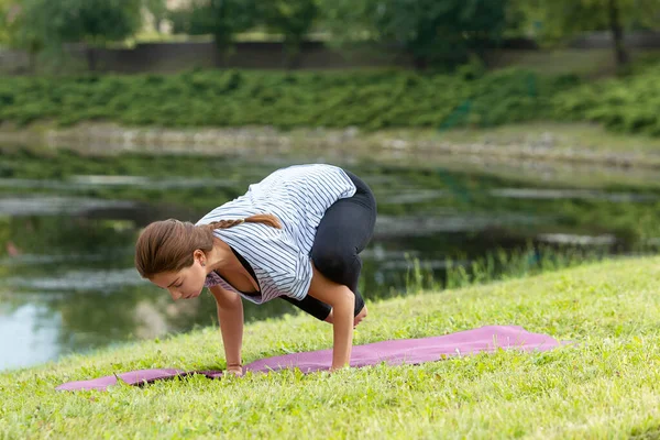 Jeune belle femme faisant de l'exercice de yoga dans un parc vert. Style de vie sain et concept de fitness . — Photo