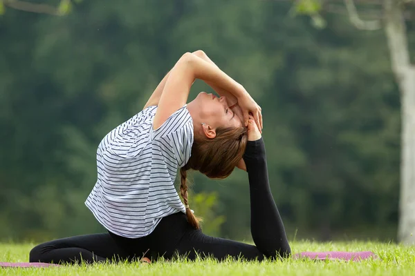 Junge schöne Frau macht Yoga-Übungen im grünen Park. gesunder Lebensstil und Fitness-Konzept. — Stockfoto