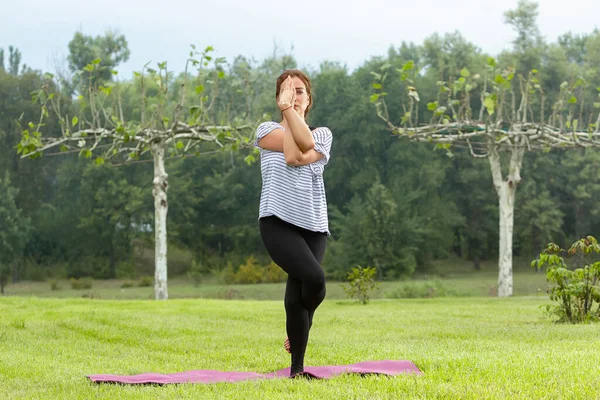 Jeune belle femme faisant de l'exercice de yoga dans un parc vert. Style de vie sain et concept de fitness . — Photo