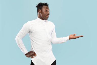 Genç Afro-Amerikalı adam mavi stüdyo arka planında izole edilmiş, insan duyguları konsepti..