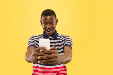 Genç Afro-Amerikalı adam sarı stüdyo arka planında izole edilmiş, insan duyguları konsepti..