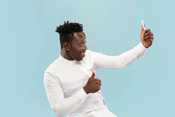 Jovem homem afro-americano isolado em fundo de estúdio azul, conceito de emoções humanas . — Fotografia de Stock