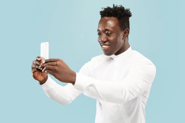 Hombre afroamericano joven aislado en fondo de estudio azul, concepto de emociones humanas . — Foto de Stock