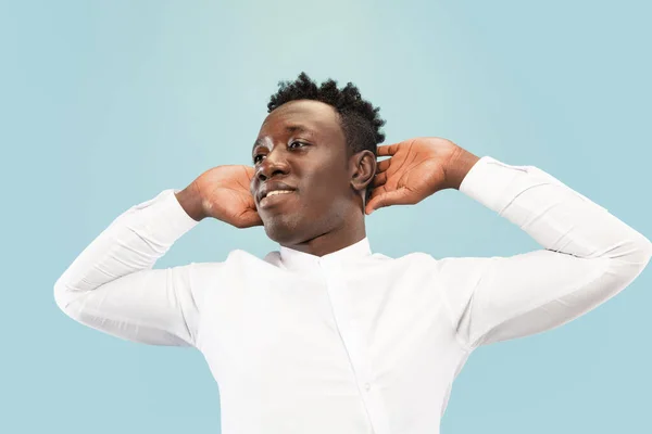 Hombre afroamericano joven aislado en fondo de estudio azul, concepto de emociones humanas . — Foto de Stock