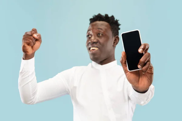 Hombre afroamericano joven aislado en fondo de estudio azul, concepto de emociones humanas . — Foto de Stock