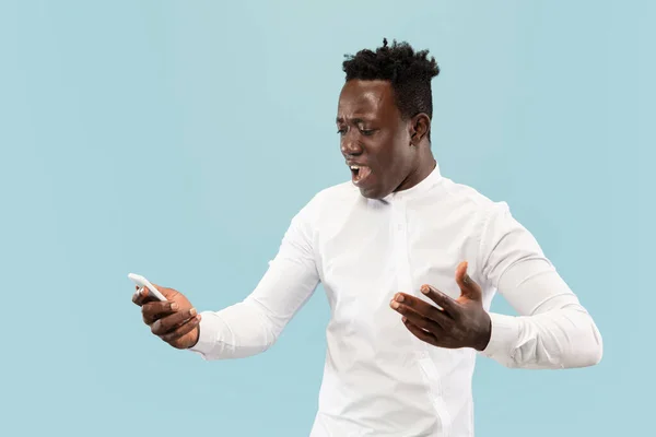 Hombre afroamericano joven aislado en fondo de estudio azul, concepto de emociones humanas . — Foto de Stock