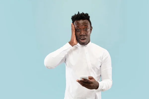 Jovem homem afro-americano isolado em fundo de estúdio azul, conceito de emoções humanas . — Fotografia de Stock