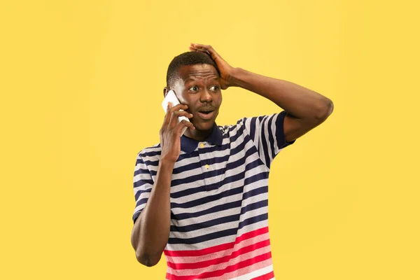 Jonge Afrikaans-Amerikaanse man geïsoleerd op gele studio achtergrond, menselijke emoties concept. — Stockfoto