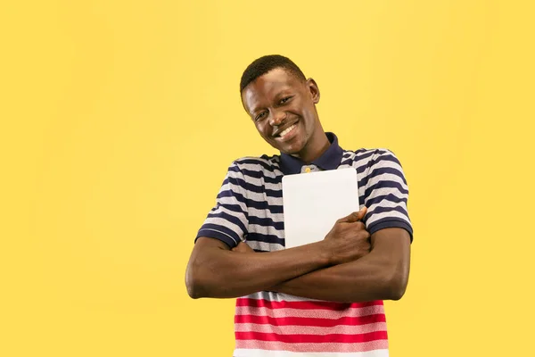 Jonge Afrikaans-Amerikaanse man geïsoleerd op gele studio achtergrond, menselijke emoties concept. — Stockfoto