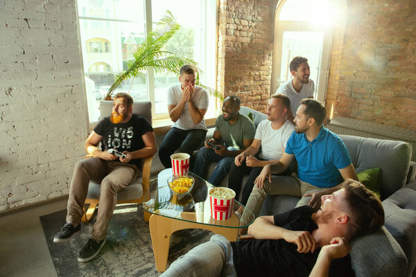 Group of excited friends playing video games at home