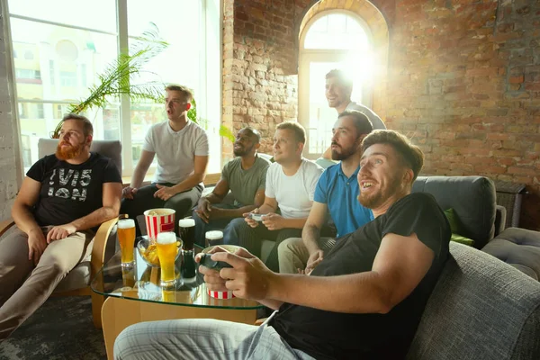 Group of excited friends playing video games at home