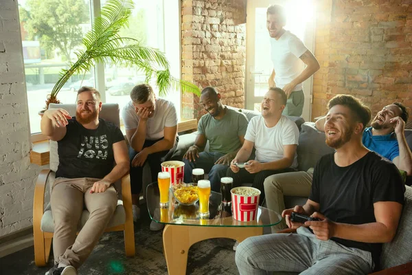 Group of excited friends playing video games at home