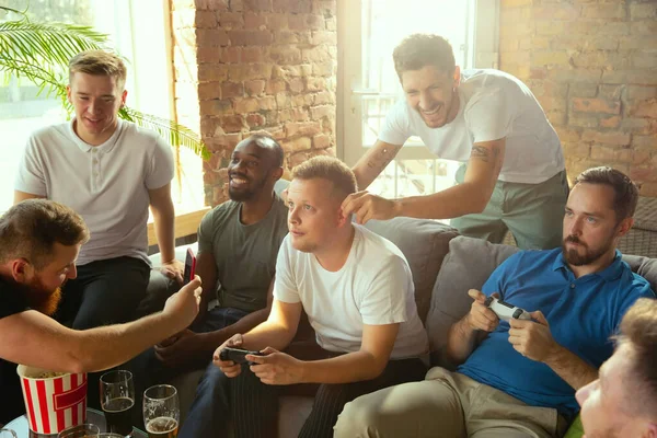 Group of excited friends playing video games at home