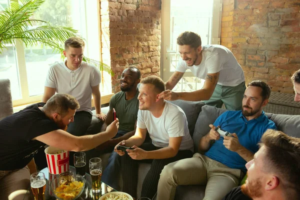 Group of excited friends playing video games at home