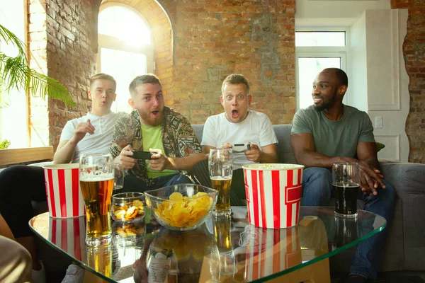 Group of excited friends playing video games at home