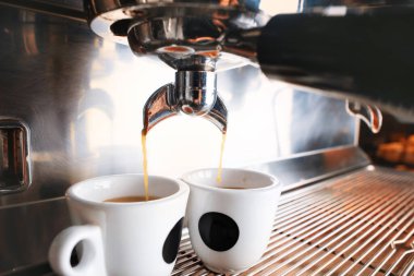 Süslü siyah espresso makinası iki fincan kahve yapıyor, kafede vurularak..