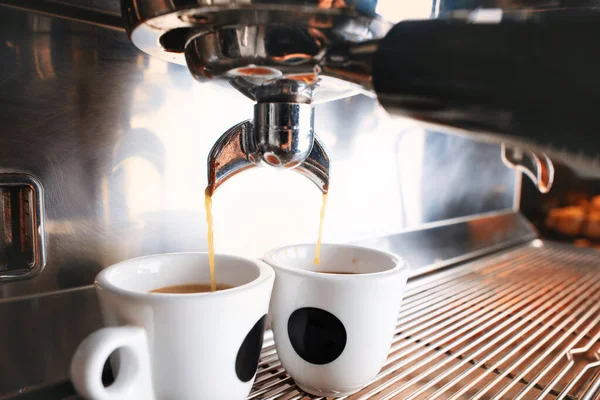 Stilvolle schwarze Espressomaschine, die zwei Tassen Kaffee braut, gedreht im Café. — Stockfoto
