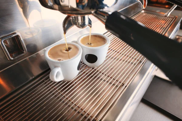 Stilvolle schwarze Espressomaschine, die zwei Tassen Kaffee braut, gedreht im Café. — Stockfoto