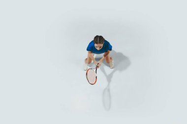 Mavi gömlekli genç bayan tenis oynuyor. Gençlik, esneklik, güç ve enerji.