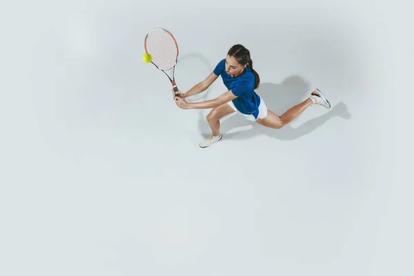 Fiatal nő kék ingben teniszezik. Ifjúság, rugalmasság, hatalom és energia. — Stock Fotó