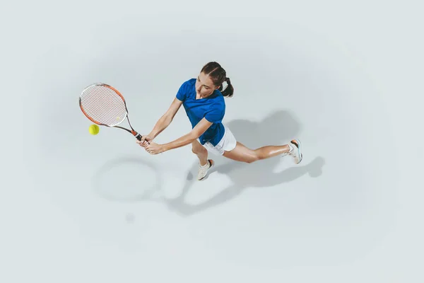 Ung kvinna i blå skjorta spelar tennis. Ungdom, flexibilitet, kraft och energi. — Stockfoto