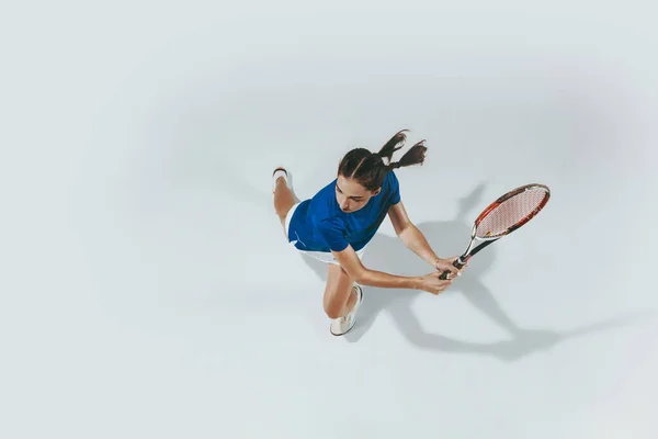 Молода жінка в блакитній сорочці грає в теніс. Молодь, гнучкість, влада та енергія . — стокове фото
