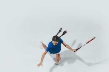 Mavi gömlekli genç bayan tenis oynuyor. Gençlik, esneklik, güç ve enerji.