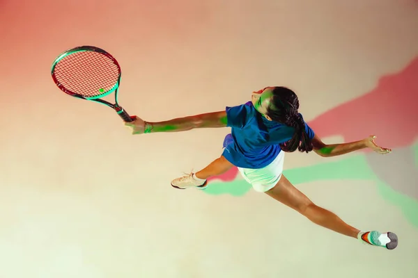 Молода жінка в синій сорочці грає в теніс у змішаному світлі. Молодь, гнучкість, влада та енергія . — стокове фото