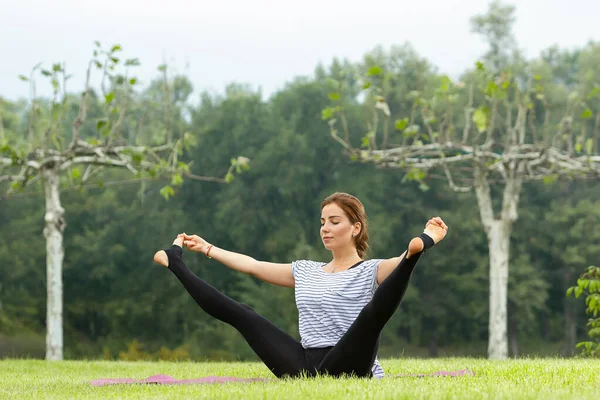 Junge schöne Frau macht Yoga-Übungen im grünen Park. gesunder Lebensstil und Fitness-Konzept. — Stockfoto