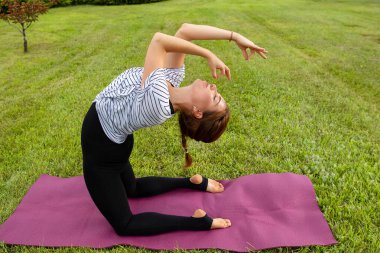 Genç ve güzel bir kadın Green Park 'ta yoga egzersizi yapıyor. Sağlıklı yaşam tarzı ve uygunluk kavramı.