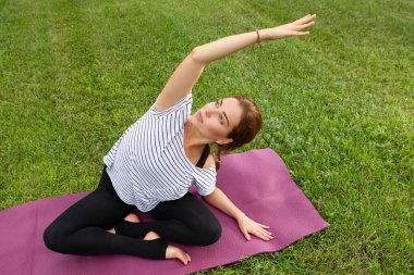 Genç ve güzel bir kadın Green Park 'ta yoga egzersizi yapıyor. Sağlıklı yaşam tarzı ve uygunluk kavramı.