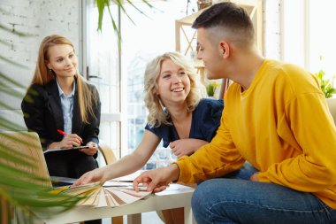 Genç bir çiftle çalışan iç mimar. Sevimli aile ve profesyonel tasarımcı veya mimar.
