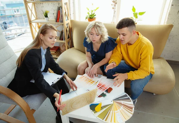 Interior designer che lavora con una giovane coppia. Bella famiglia e designer professionista o architetto . — Foto Stock