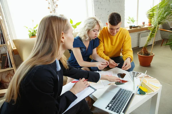 Diseñador de interiores trabajando con parejas jóvenes. Precioso diseñador familiar y profesional o arquitecto . — Foto de Stock