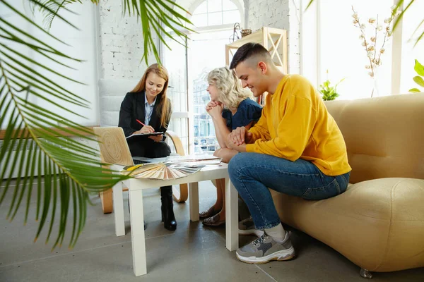 Interior designer che lavora con una giovane coppia. Bella famiglia e designer professionista o architetto . — Foto Stock