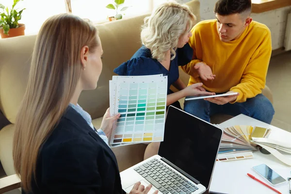 Interior designer che lavora con una giovane coppia. Bella famiglia e designer professionista o architetto . — Foto Stock