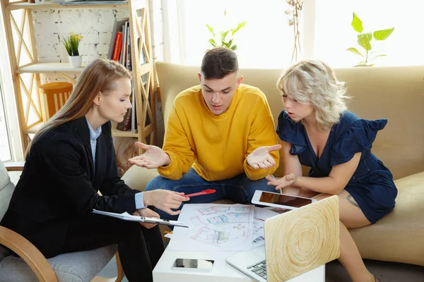 Innenarchitektin bei der Arbeit mit jungen Paaren. schöne Familie und professioneller Designer oder Architekt. — Stockfoto