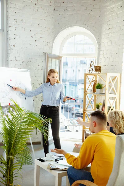 Diseñador de interiores trabajando con parejas jóvenes. Precioso diseñador familiar y profesional o arquitecto . — Foto de Stock