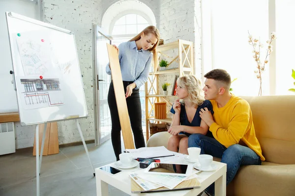 Diseñador de interiores trabajando con parejas jóvenes. Precioso diseñador familiar y profesional o arquitecto . — Foto de Stock