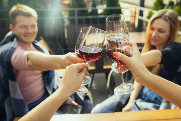 Gente tintineando vasos con vino en la terraza de verano de la cafetería o restaurante. Primer plano, estilo de vida . — Foto de Stock