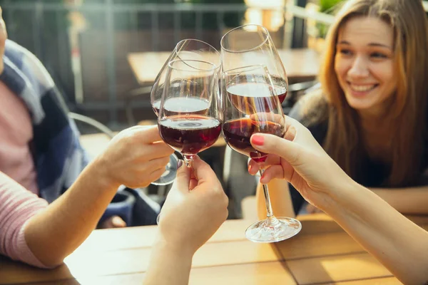 Gente tintineando vasos con vino en la terraza de verano de la cafetería o restaurante. Primer plano, estilo de vida . — Foto de Stock